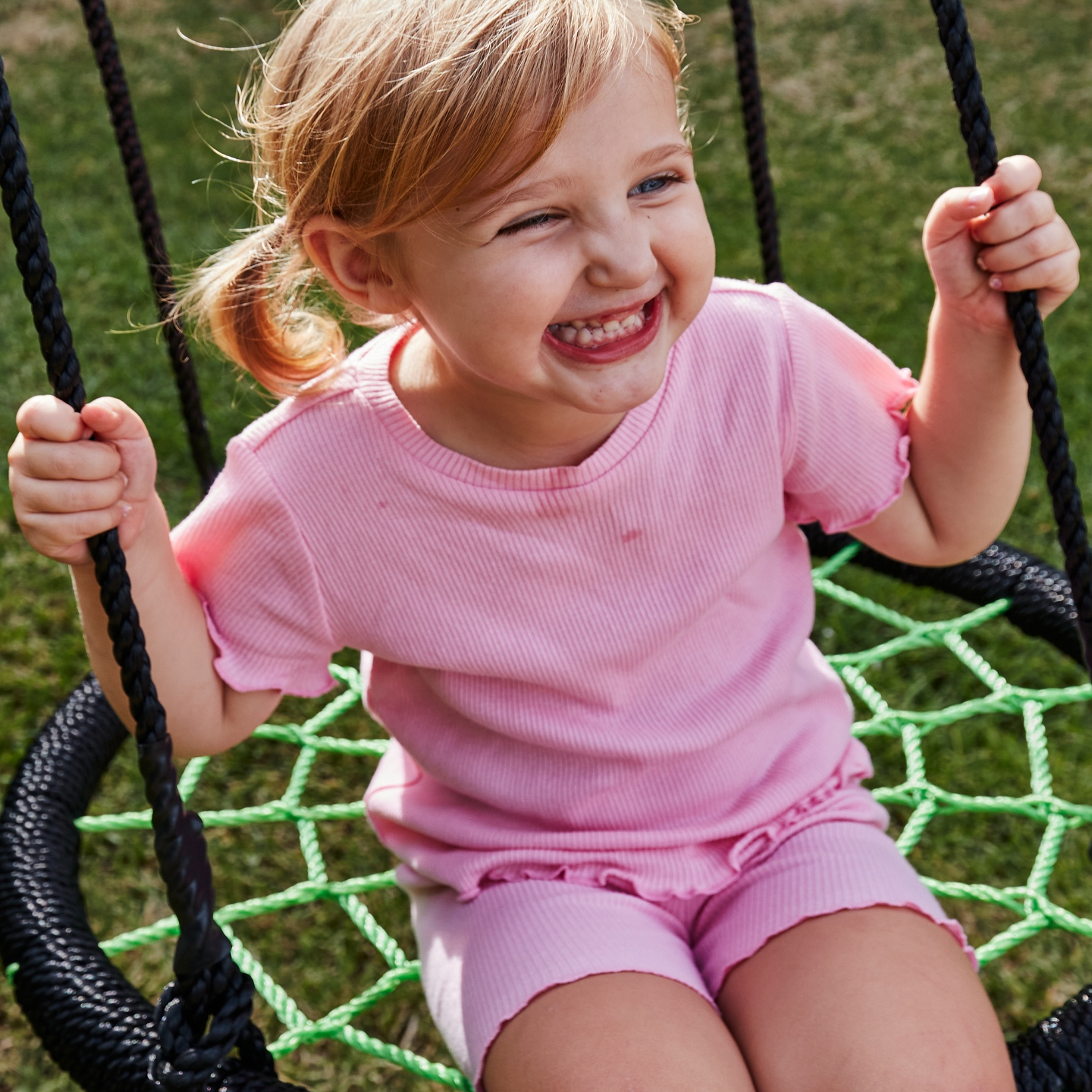 Child in a pink outfit on a swing set