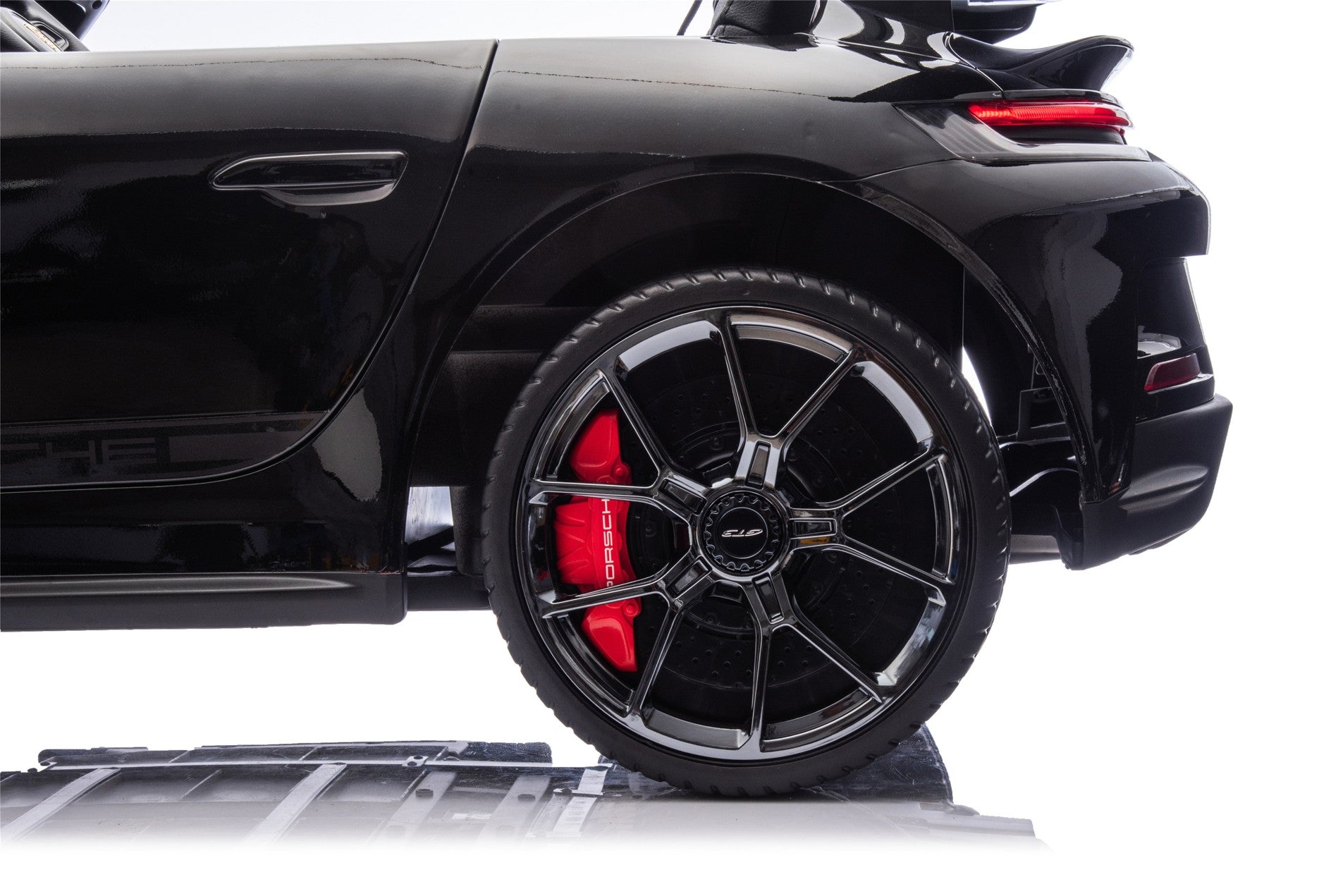 Close-up of a black car wheel with red brake caliper on a white background