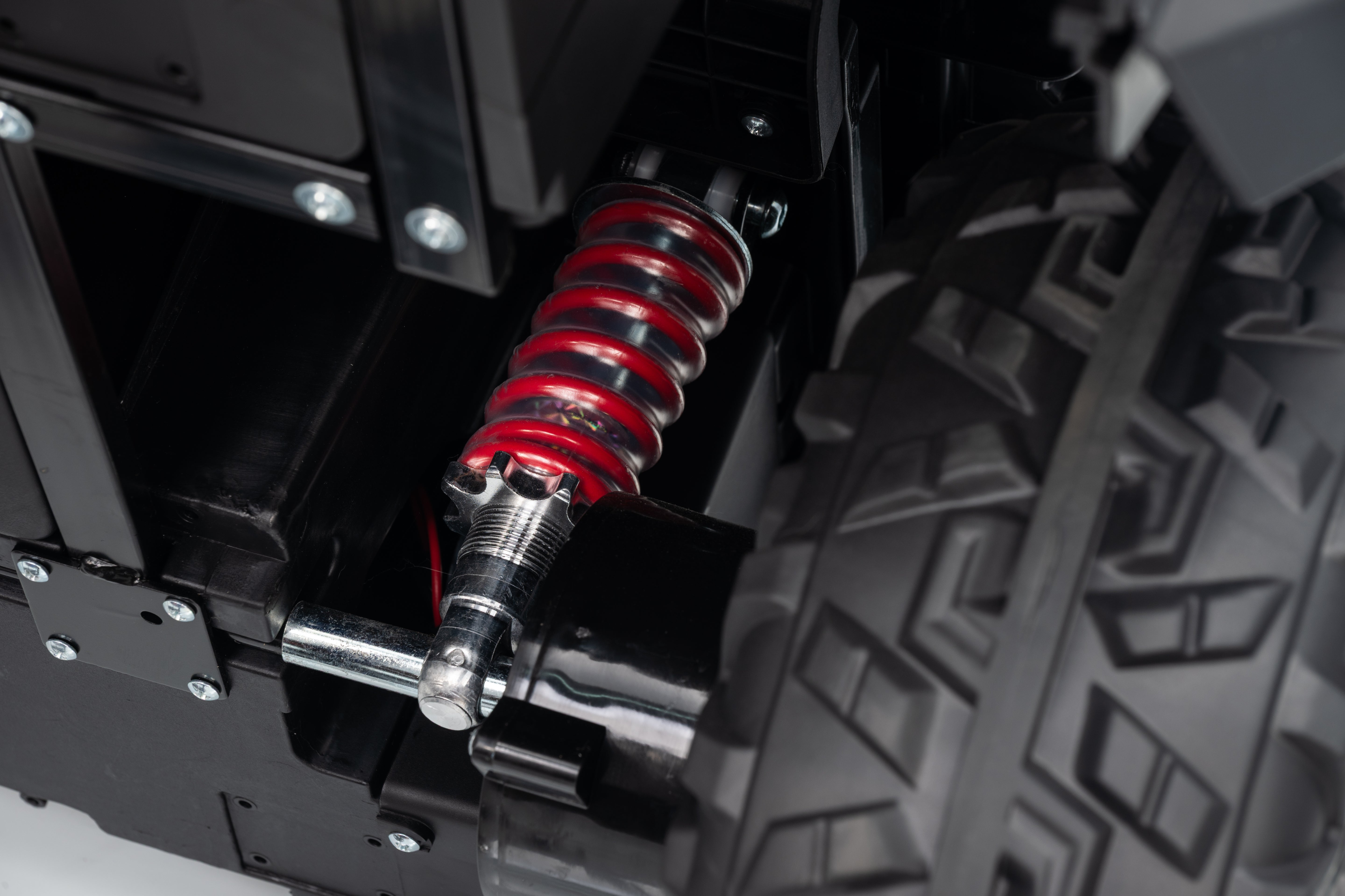 Close-up of a suspension system on a vehicle with a red shock absorber.
