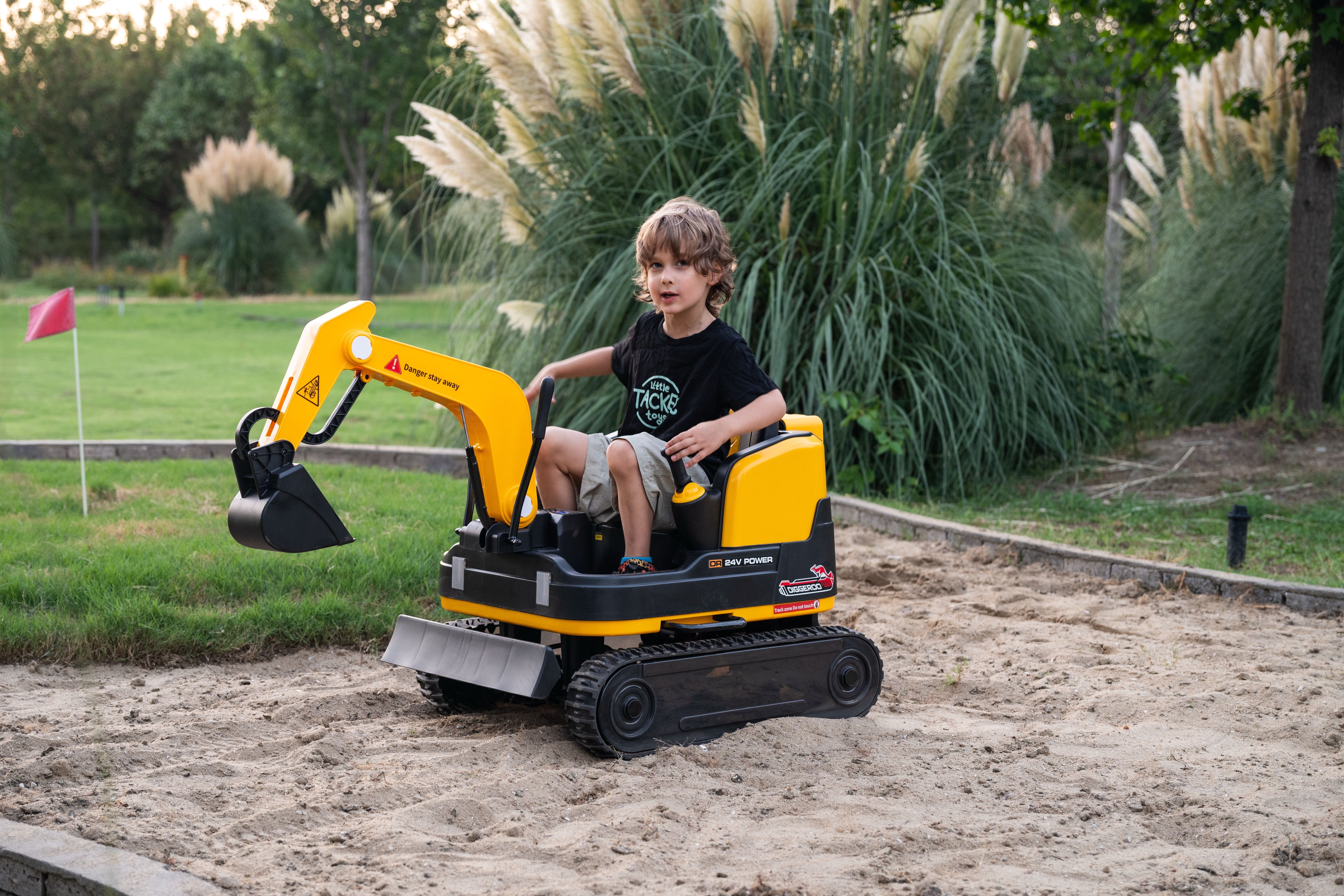 Child playing with a 24 v toy excavator in an outdoor setting