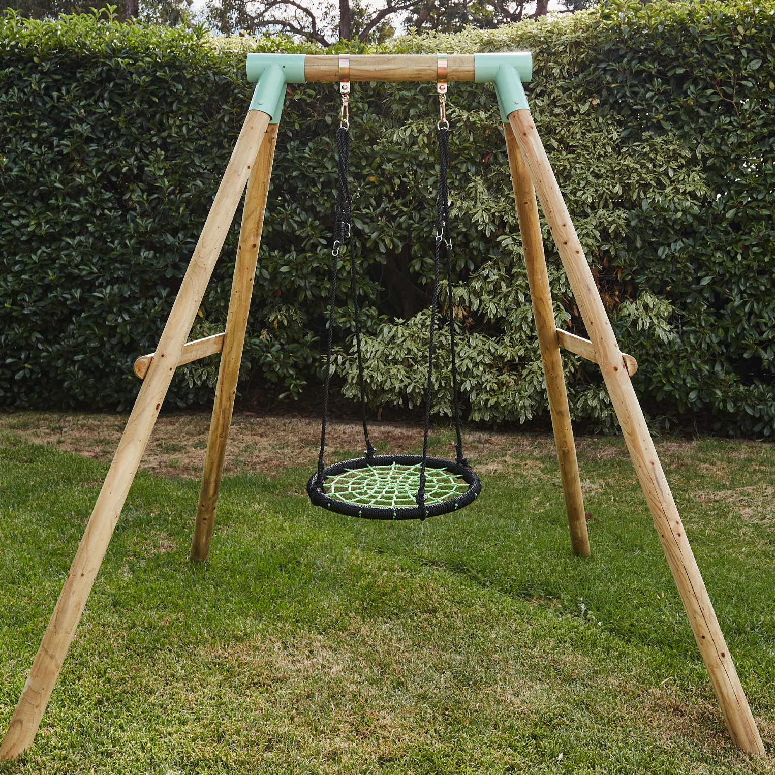 Wooden swing set with a green seat in a backyard setting