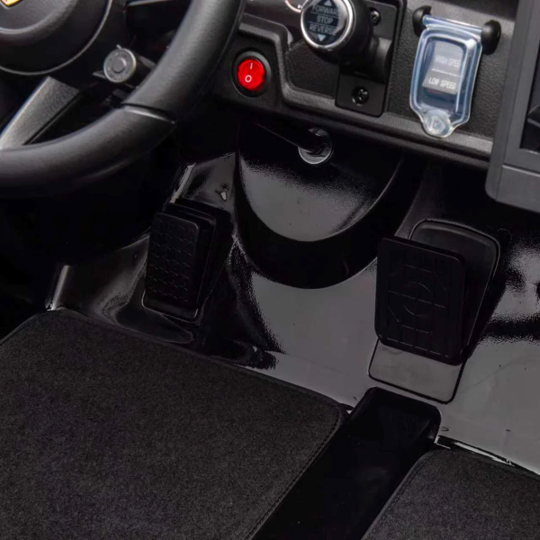 Close-up of a vehicle's interior with steering wheel, dashboard, and pedals.
