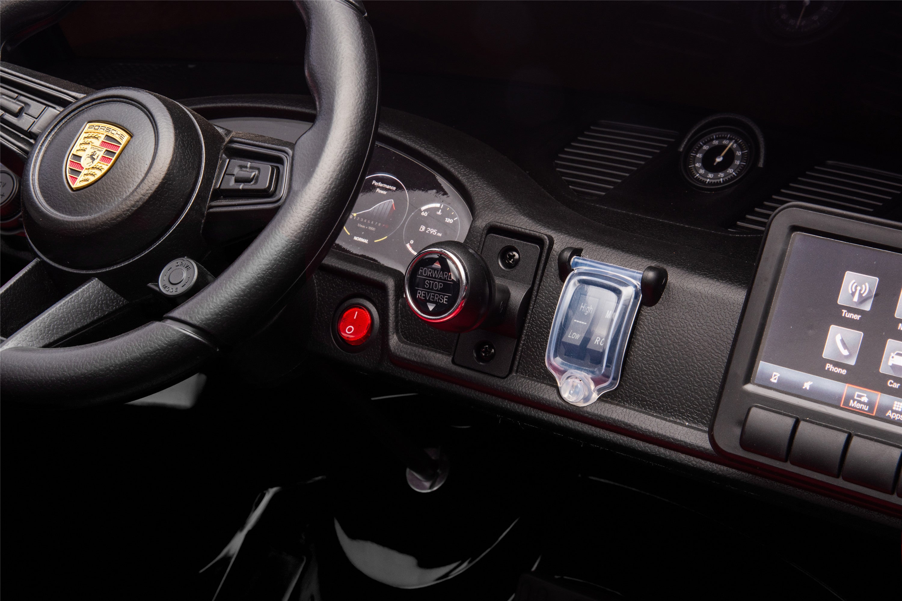 Car dashboard with steering wheel and control panel, featuring a Porsche logo.