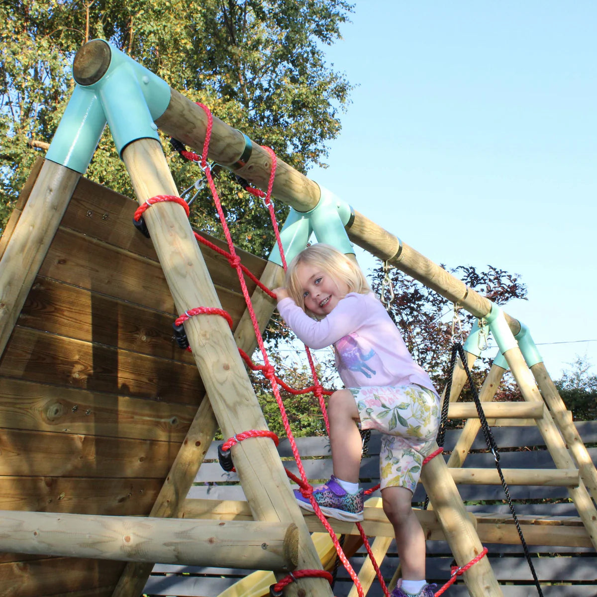 Wooden swing climbing wall with red climbing net. Blue net swing