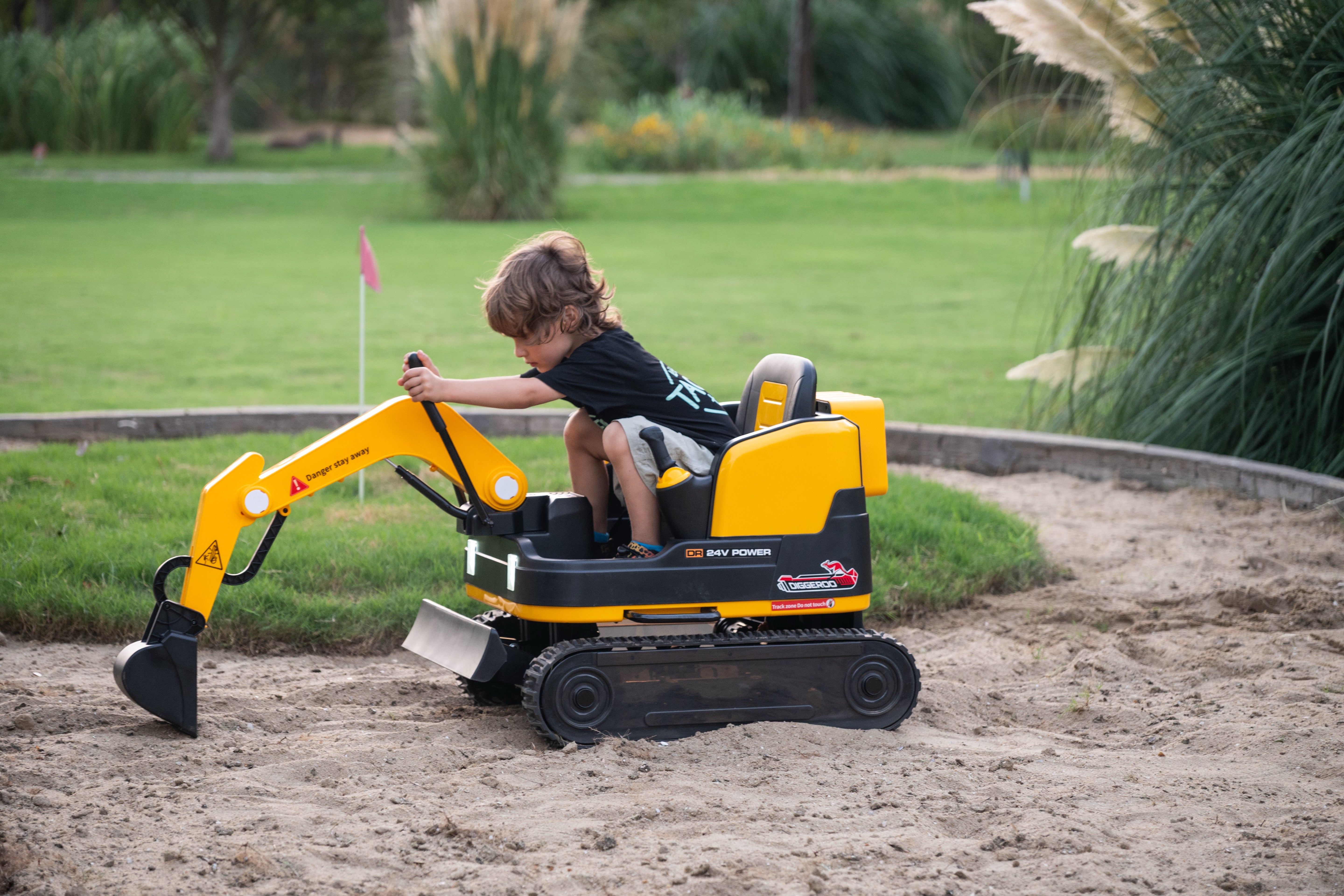 Child playing with a toy excavator on a grassy area