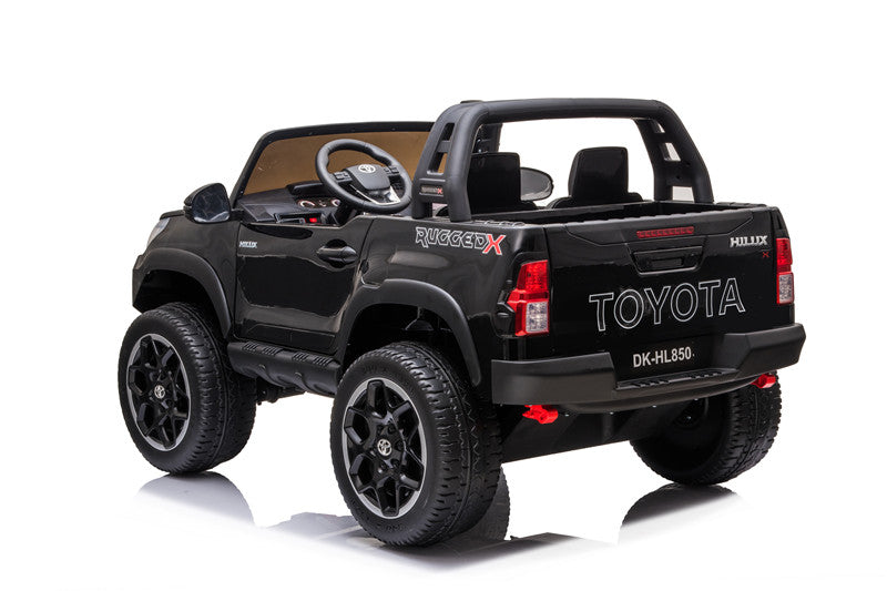 Rear-left angle of the Toyota Hilux Rugged X kids’ 4WD ride-on with black alloy wheels.