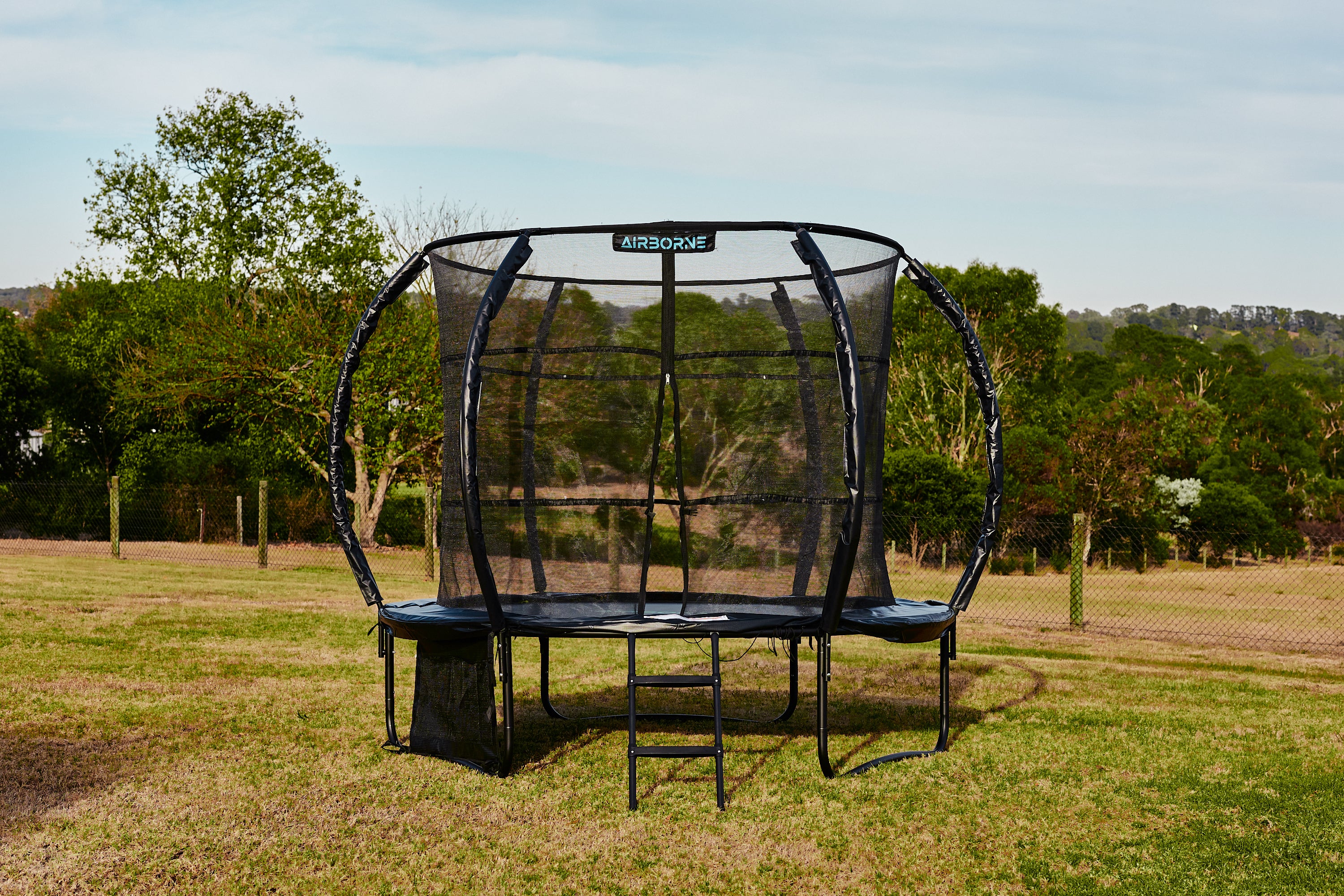 Trampoline with safety net in a grassy outdoor area