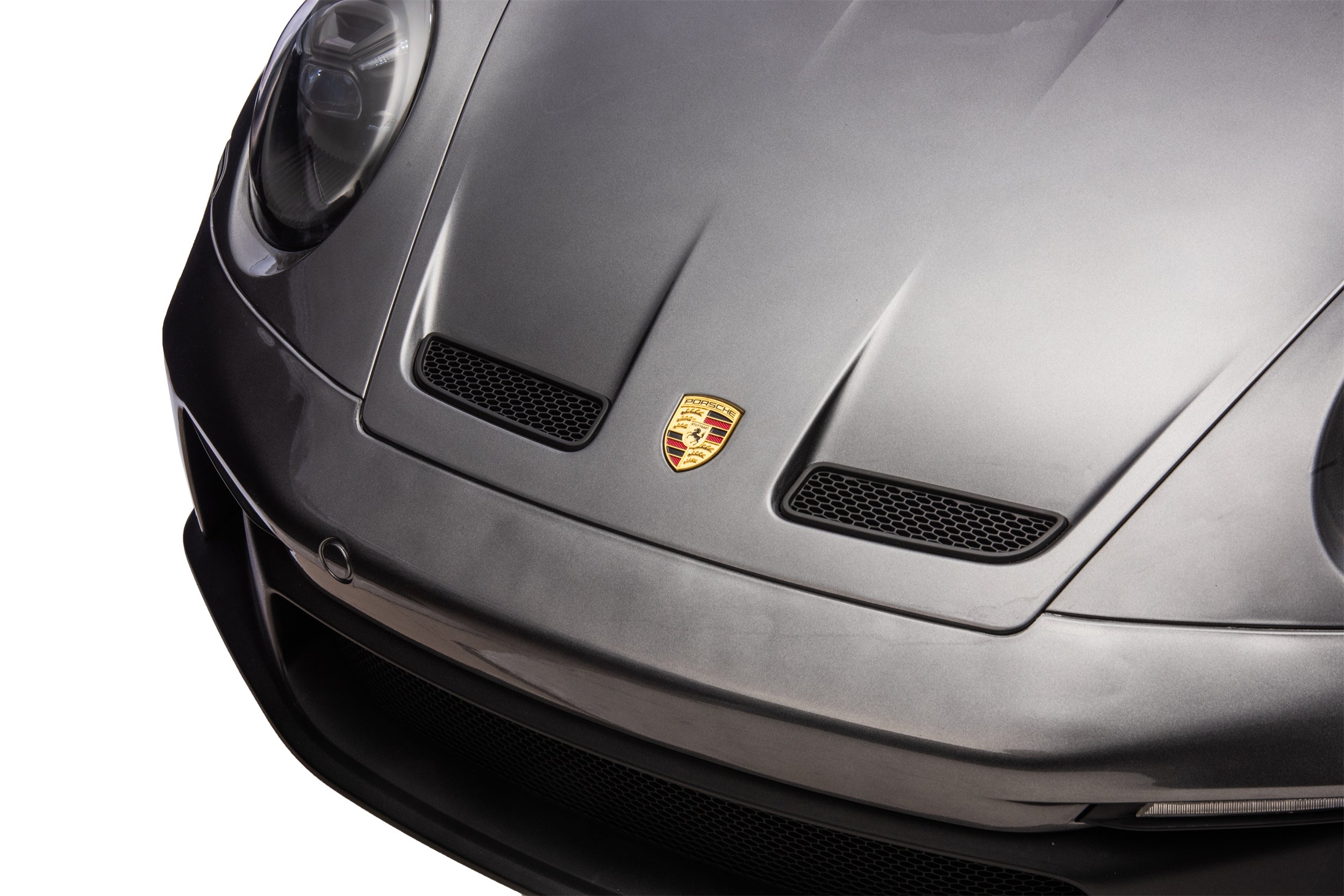 Close-up of a Porsche car front with logo on a white background