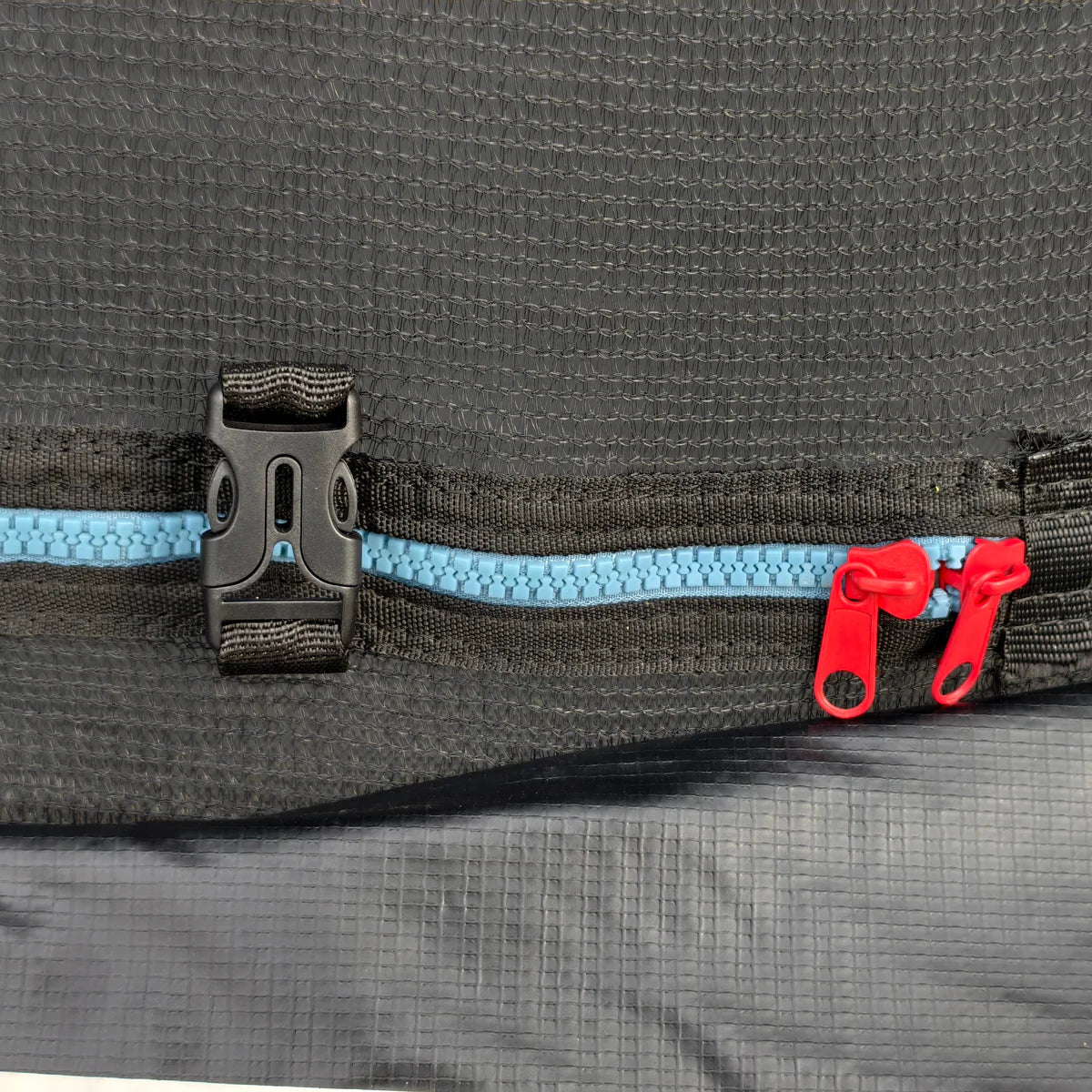 Close-up of a black bag with a blue zipper and red pull tab on a gray background