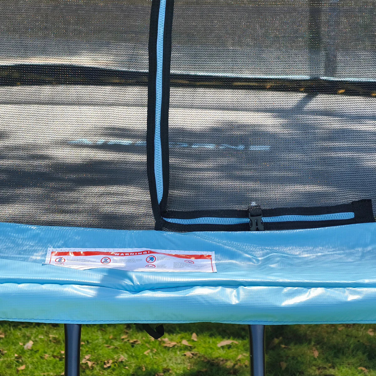Trampoline with safety net and blue padding on grass
