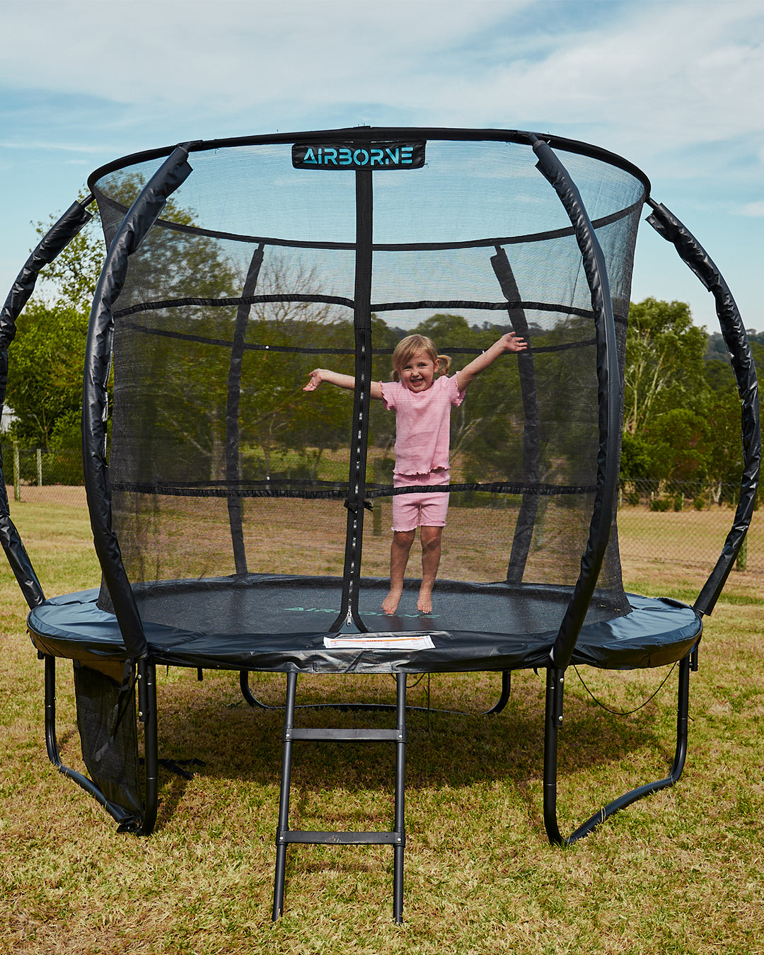 Child playing on a trampoline with safety net in an outdoor setting