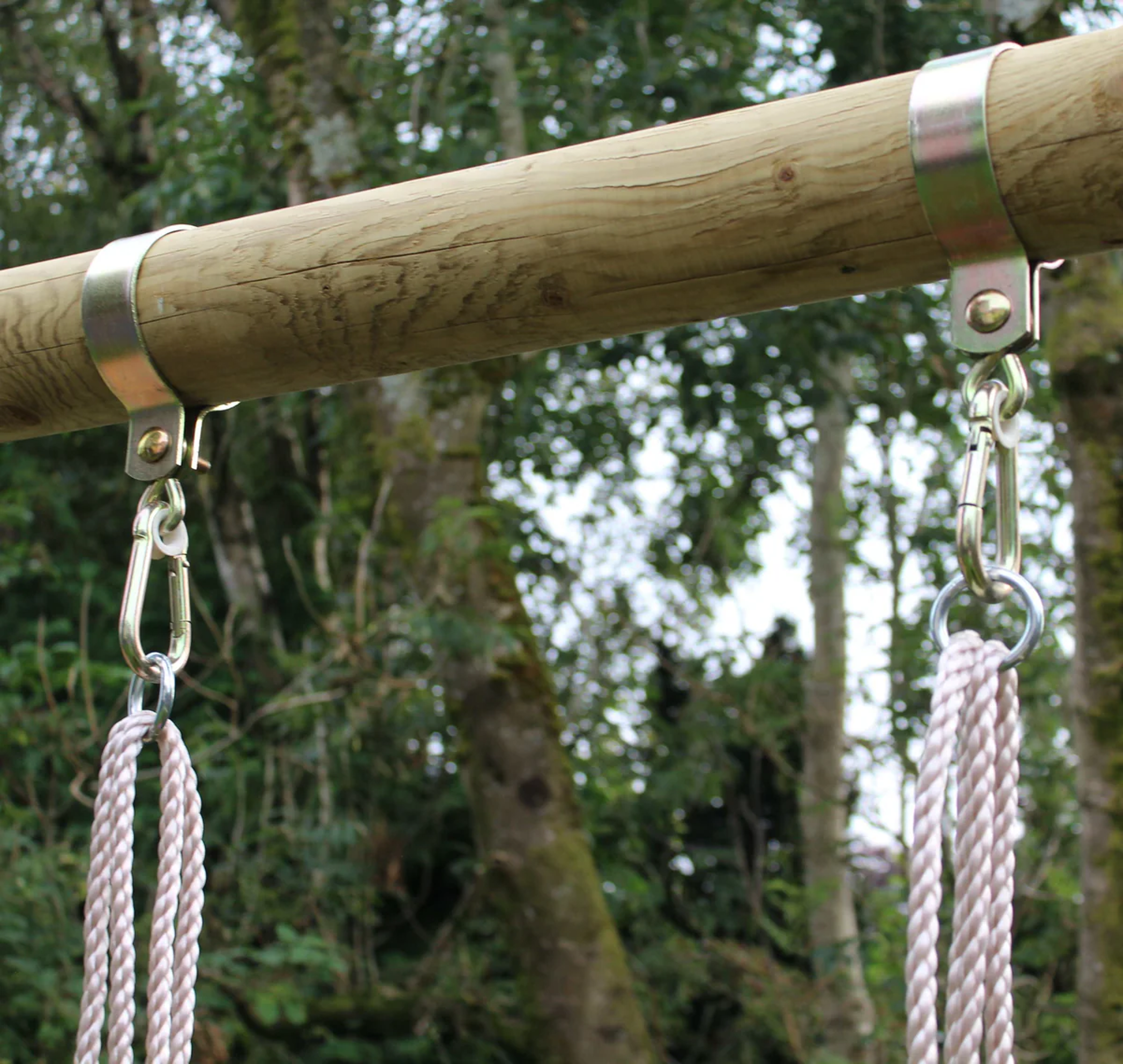Wooden swing set with ropes against a forest background