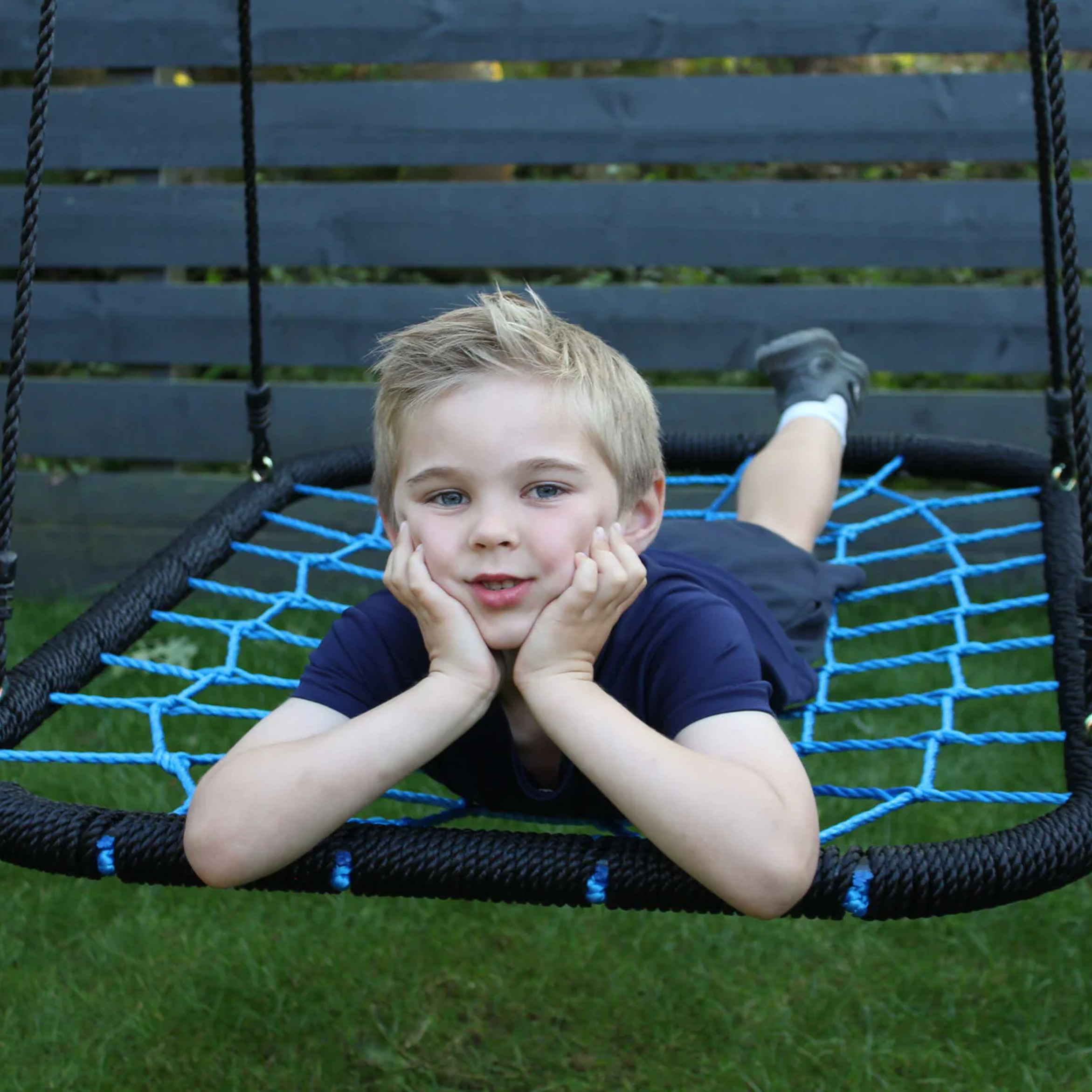 Child lying on a round net swing in a garden