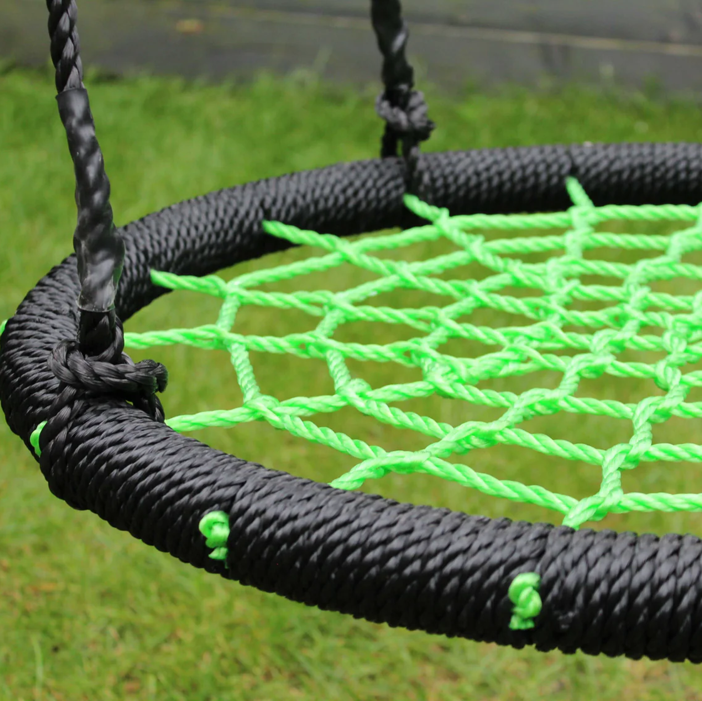 Close-up of a green and black rope swing on grass