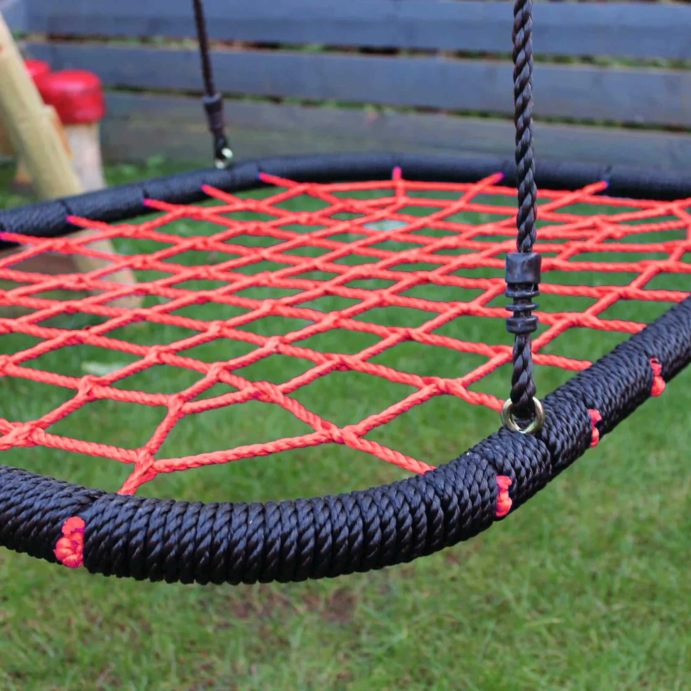 Close-up of a red and black rope swing on grass