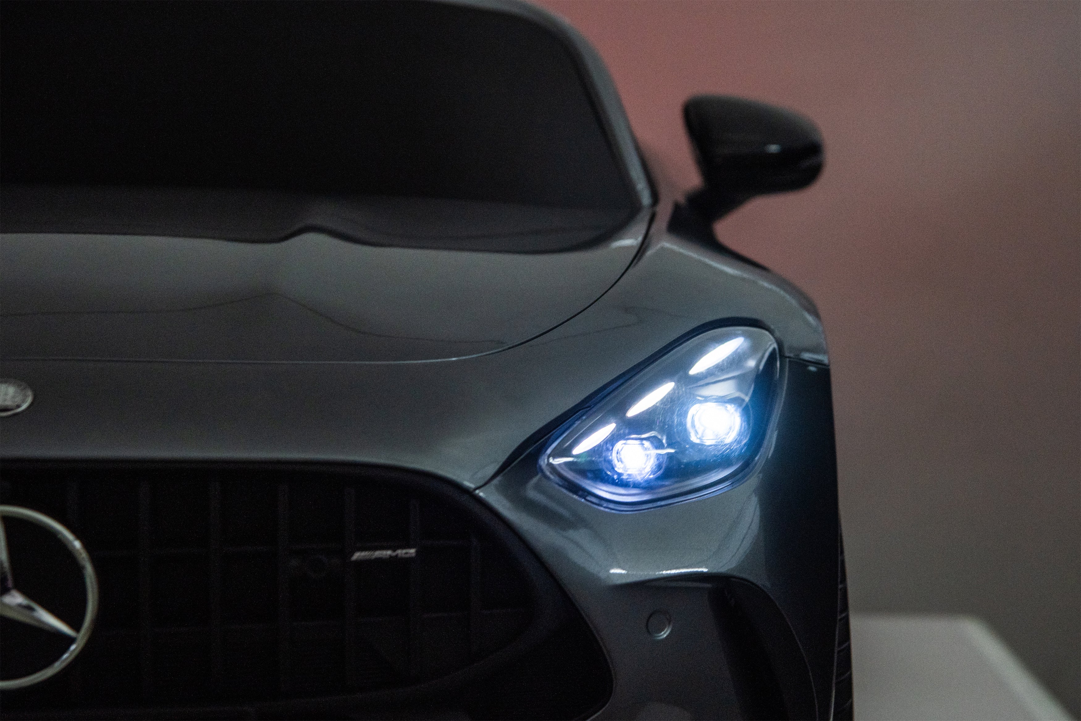 Close-up of a Mercedes-Benz car headlight with the brand logo visible.