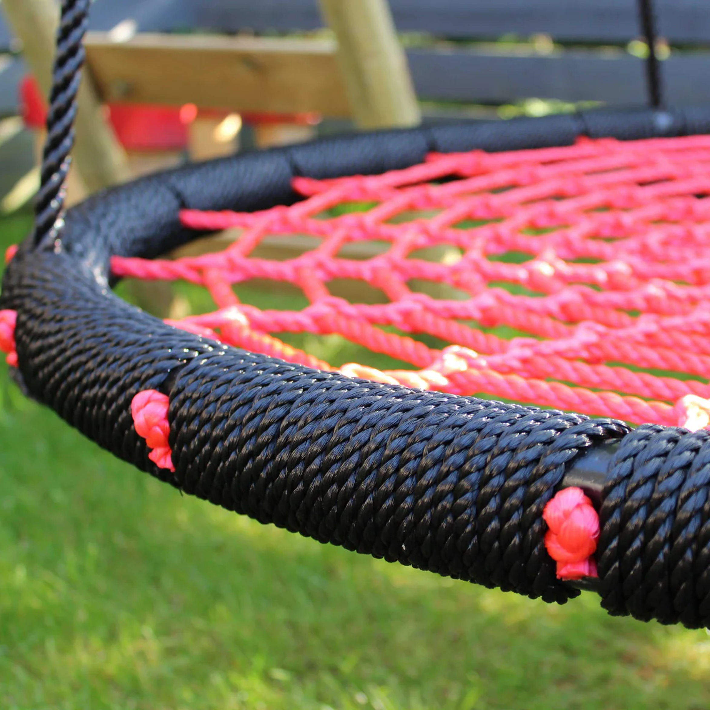 Close-up of a red and black rope swing on grass