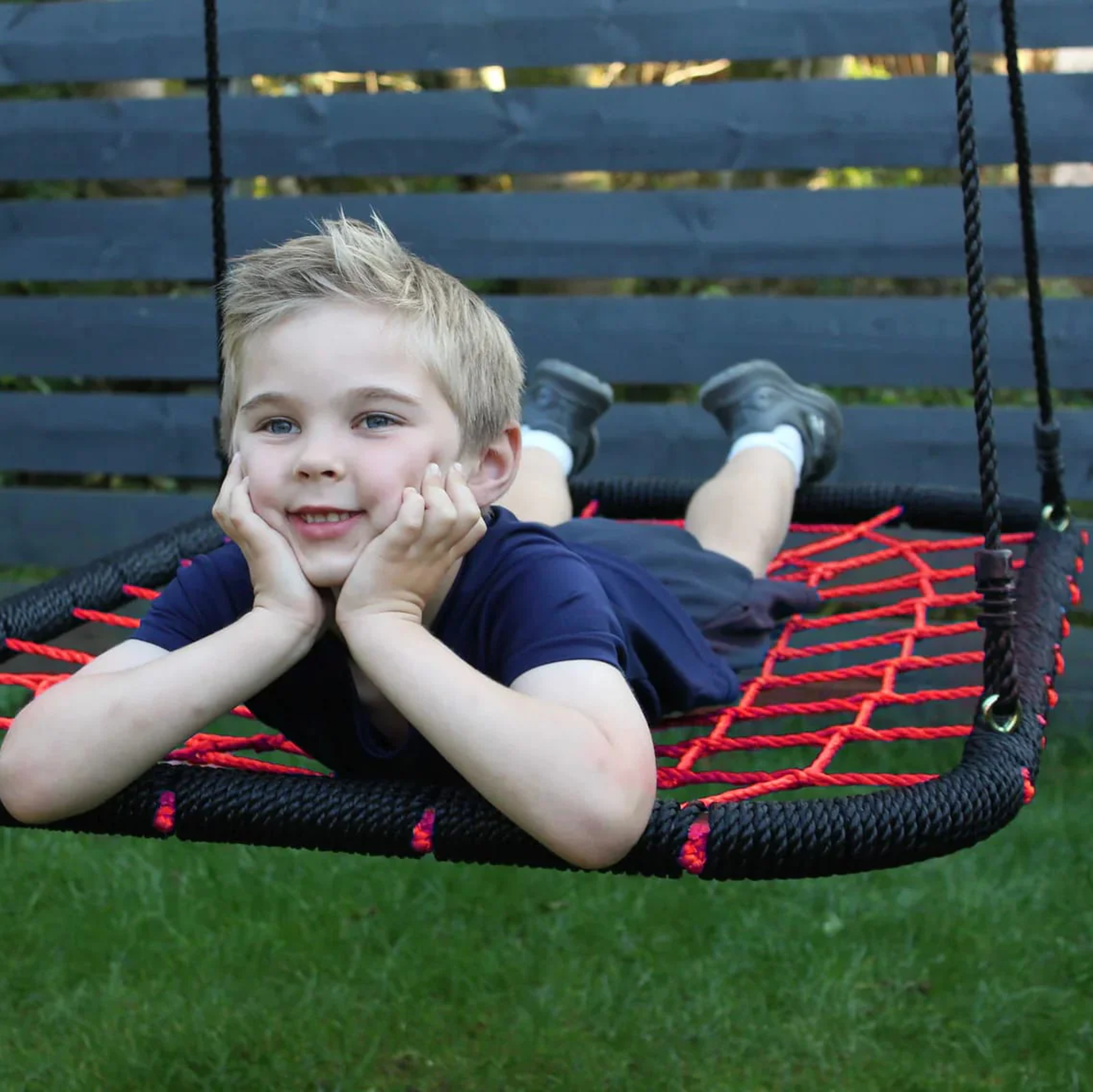Child on a red and black swing set in a garden