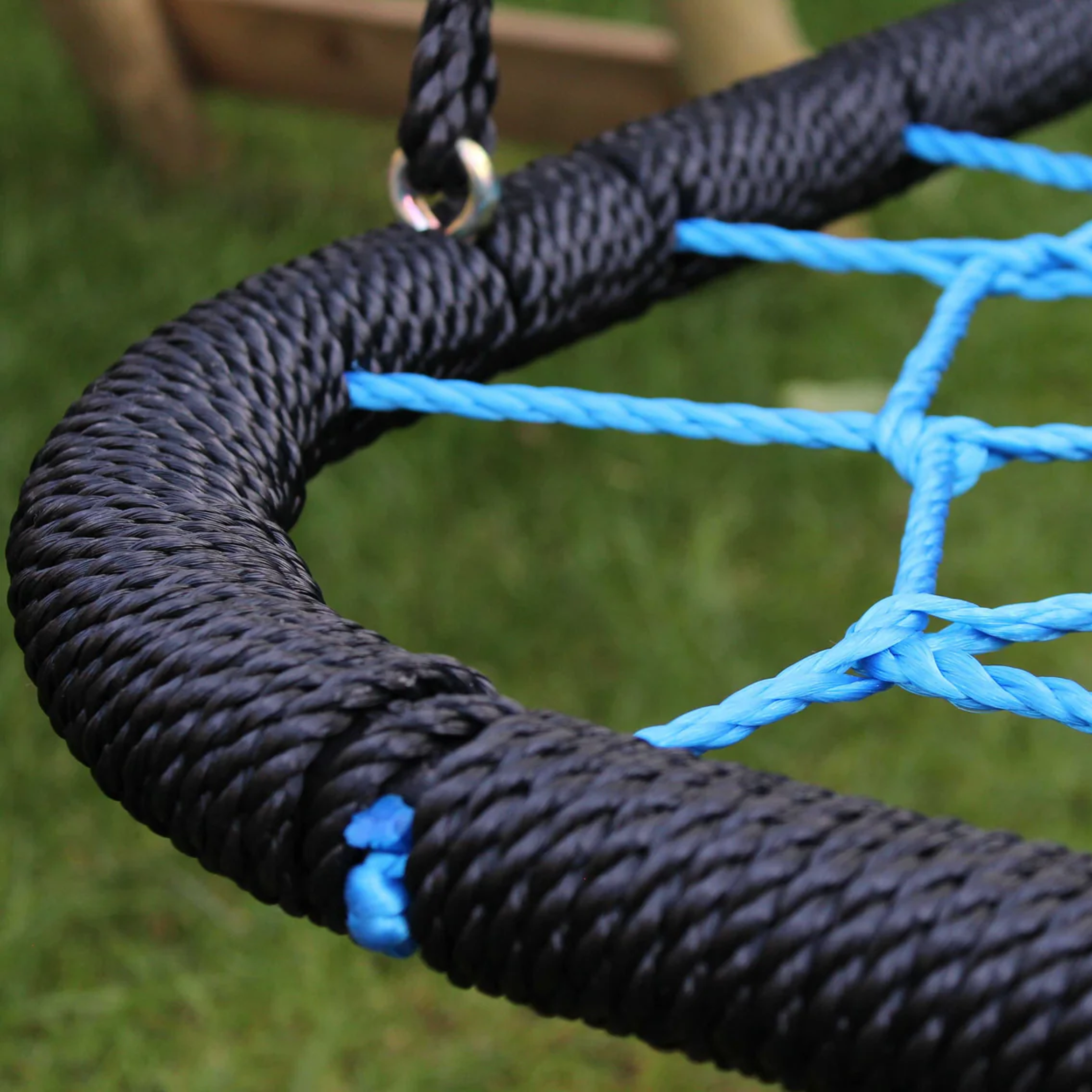 Close-up of a blue and black rope swing on grass