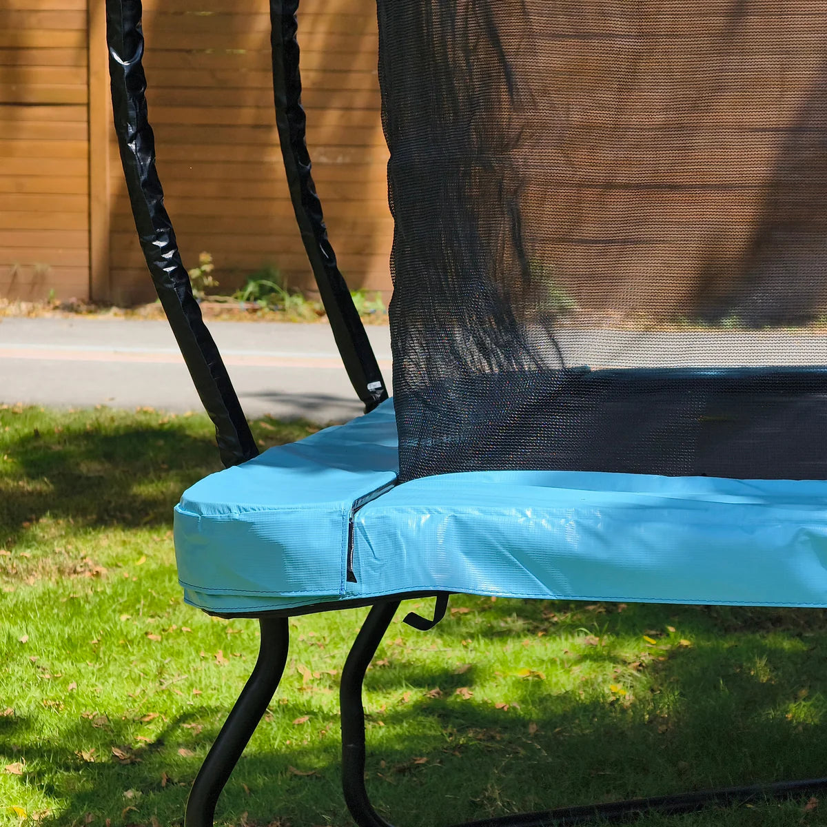 Trampoline with blue safety pad and black netting on grass