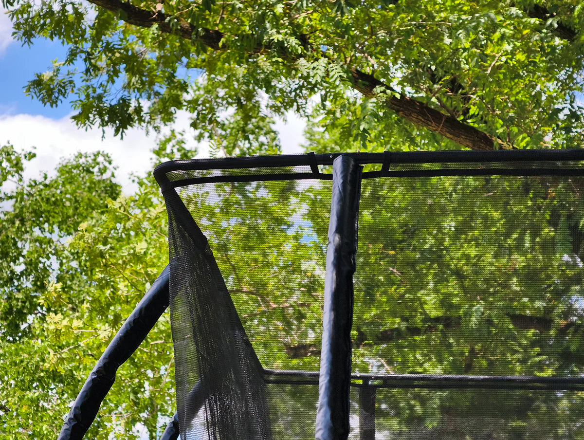 Top of a trampoline with trees and blue sky in the background