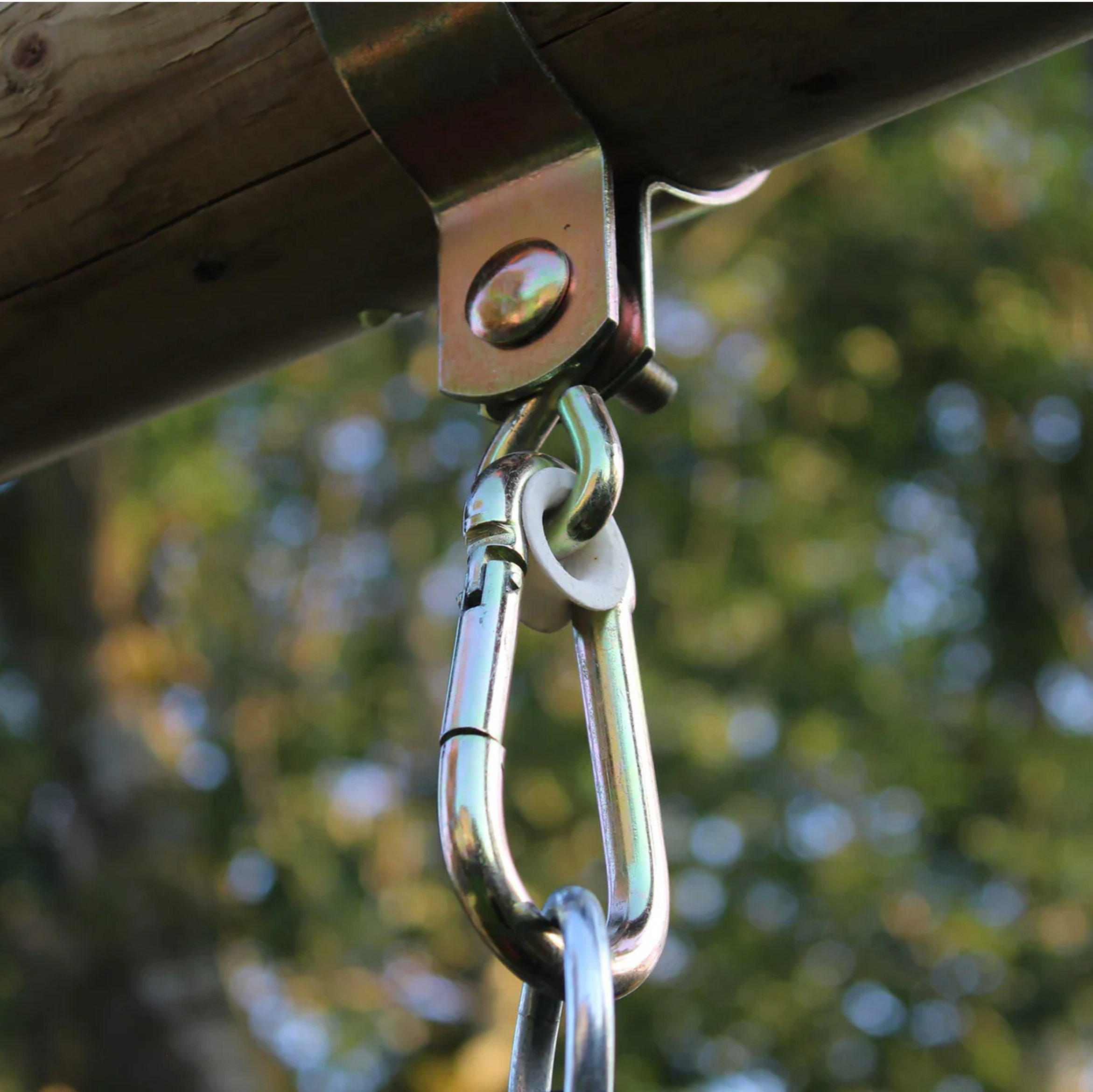 Metal swing hook attached to a wooden structure with a blurred natural background