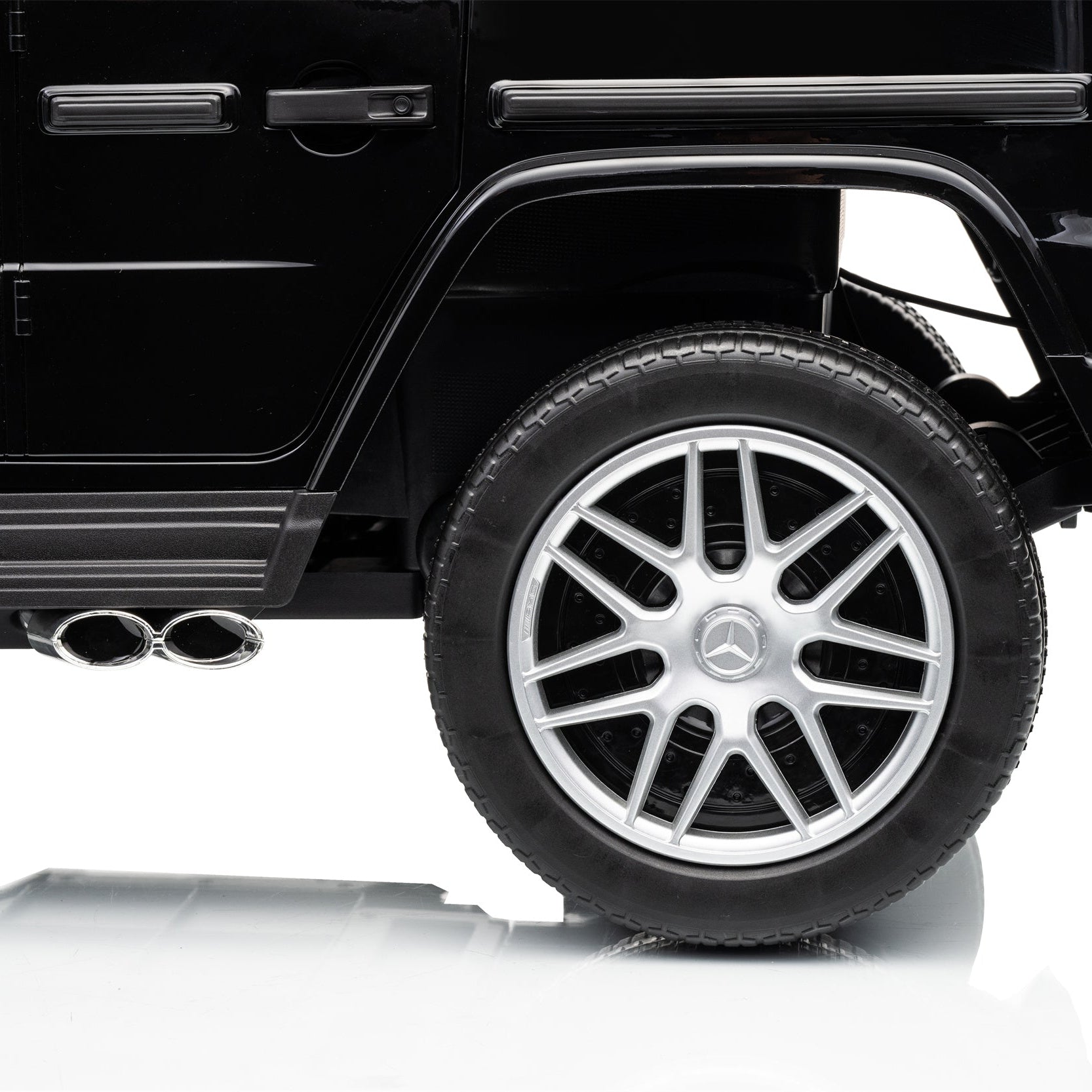 Close-up of the rear wheel and side body of a black Mercedes-Benz vehicle on a white studio background, showing the silver multi-spoke wheel and Mercedes star emblem.
