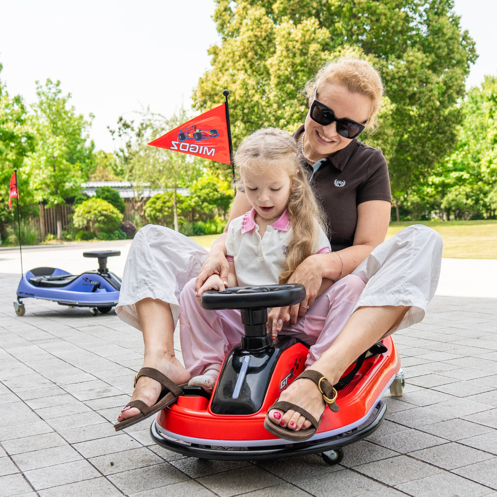 A woman and a young girl are riding in a red and black go-kart outdoors on a paved area, with trees and another blue go-kart visible in the background. The go-kart has a small red flag attached with the brand name 'SODIM'.