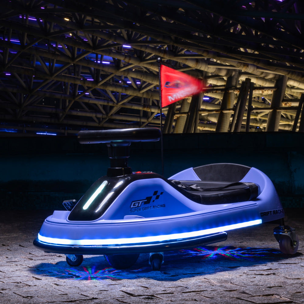 A futuristic electric go-kart with a light blue and white body, black seat, and glowing blue LED strip, parked on a stone floor inside a large industrial structure with a red flag in the background.
