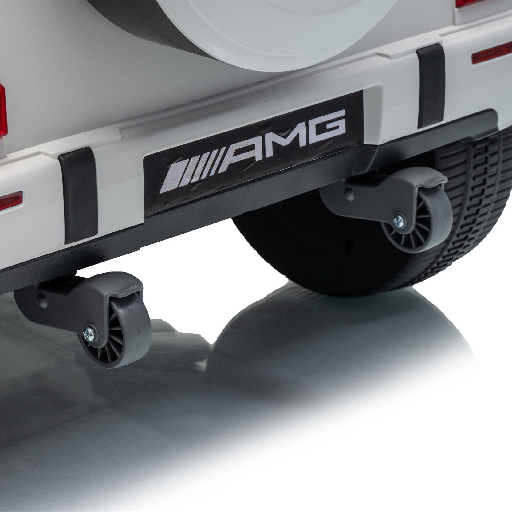 Close-up of the rear bumper area of a white vehicle with black protective trim, a visible AMG badge, and a small black underbody wheel or caster mounted below the bumper.