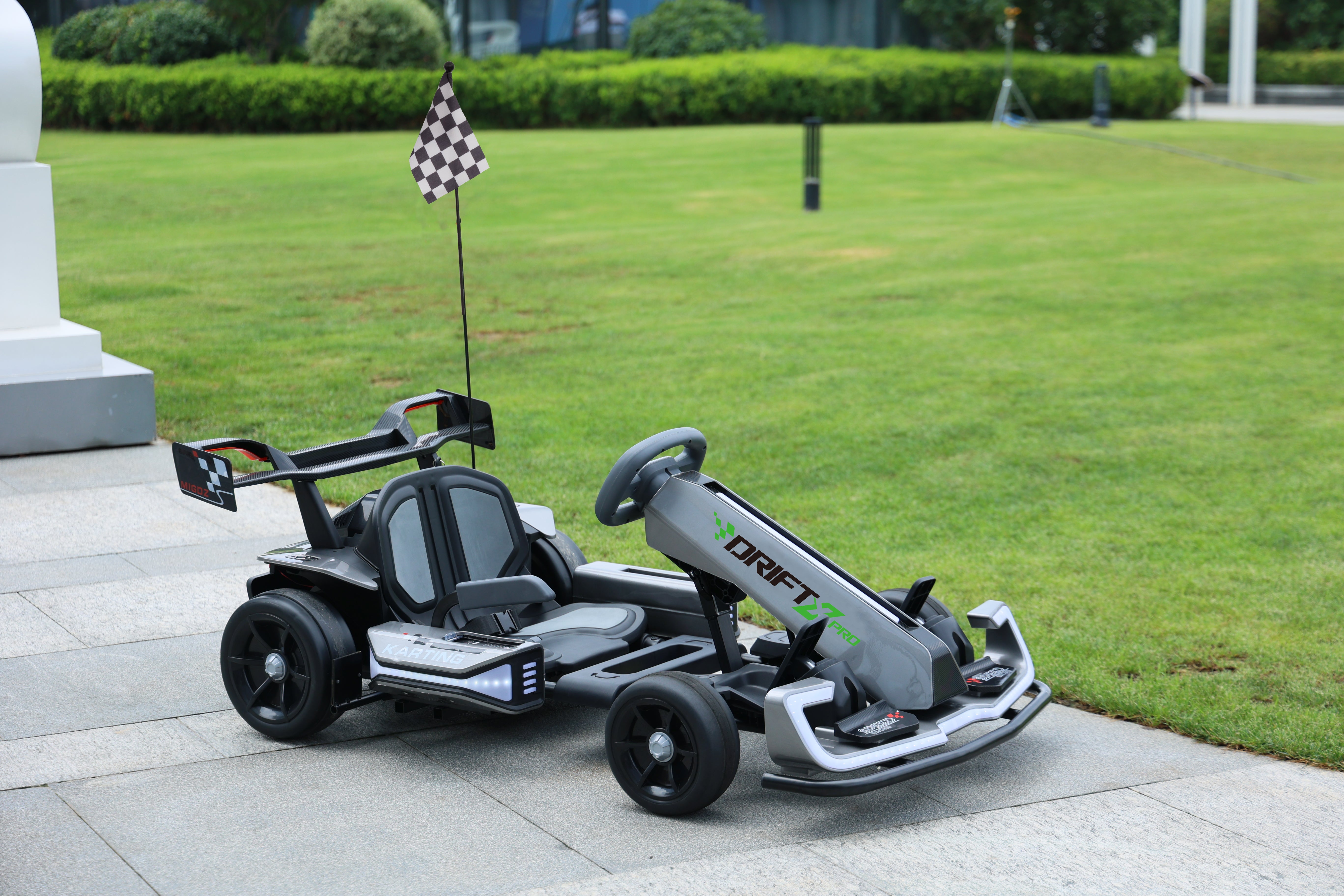 Children's toy go-kart on a paved area with grass in the background