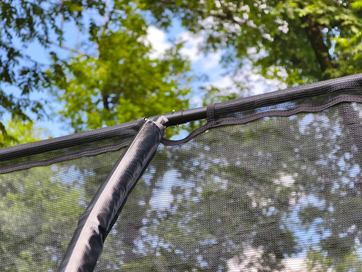 Close-up of a trampoline mesh with trees in the background