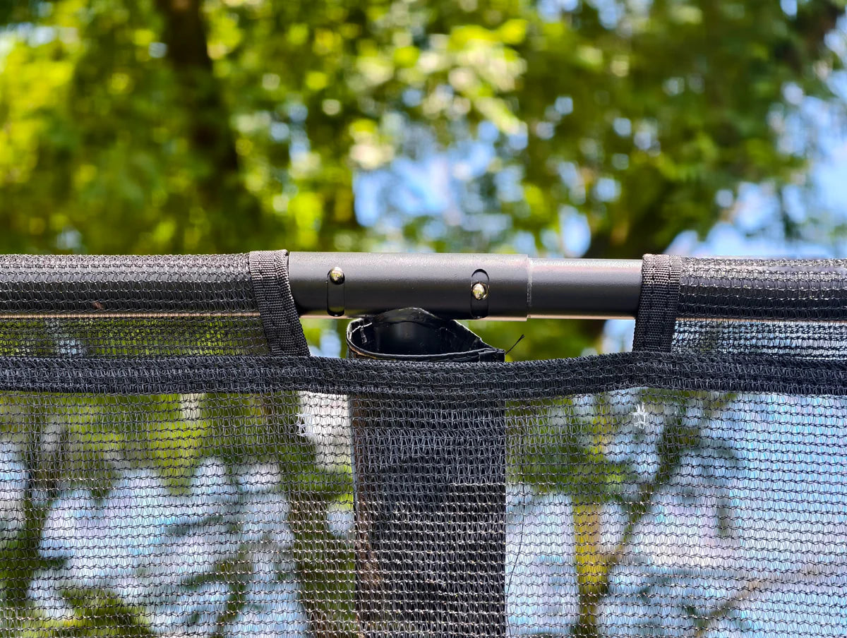 Close-up of a black mesh screen with a clip against a blurred natural background