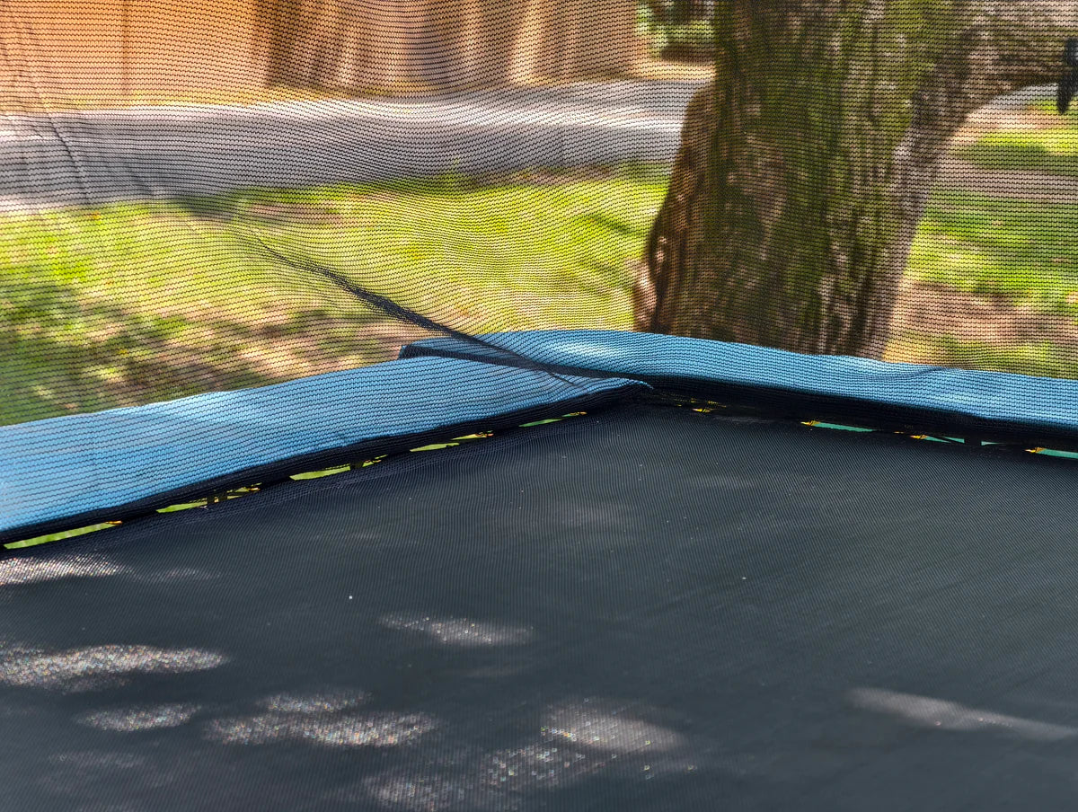 Close-up of a trampoline with a tree and grass in the background