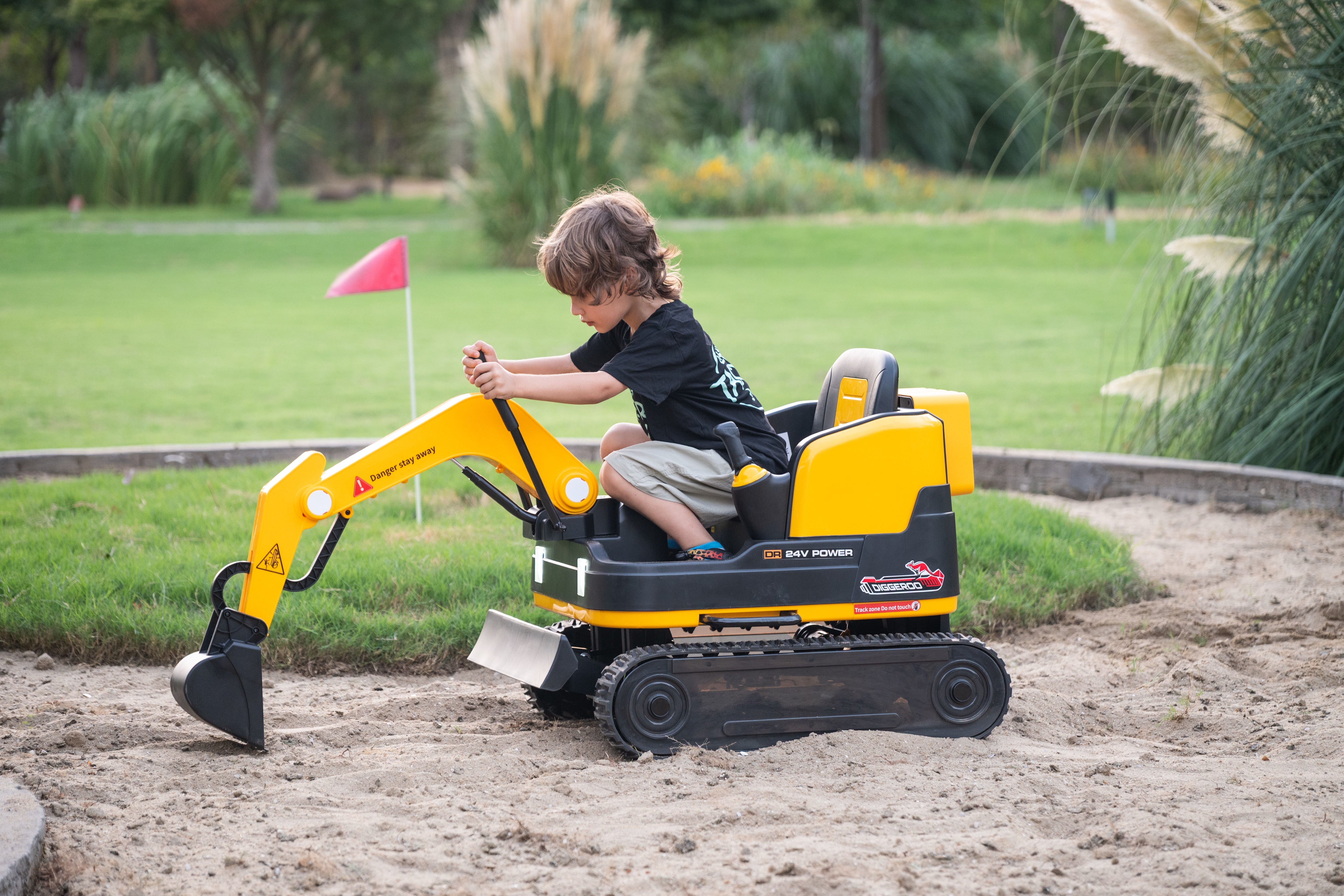 Child playing on a 24v ride on  excavator in an outdoor setting